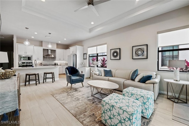 living area featuring light wood finished floors, a raised ceiling, a ceiling fan, and recessed lighting