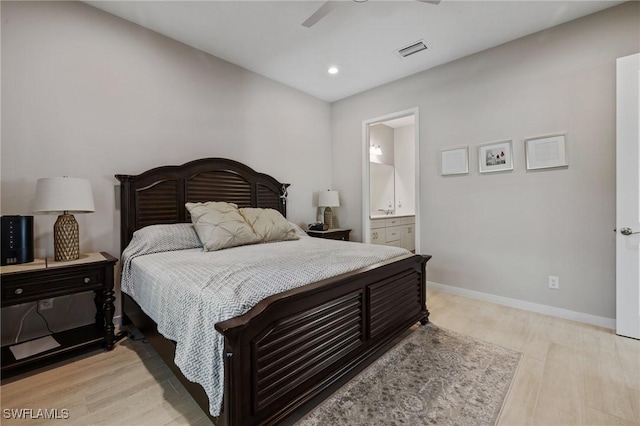 bedroom featuring light wood-style floors, visible vents, ensuite bath, and baseboards