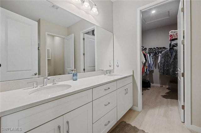 bathroom with toilet, double vanity, a sink, and wood finished floors