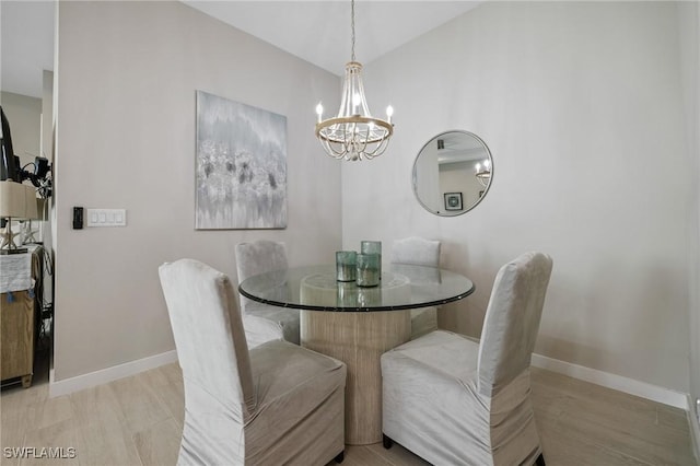 dining area with a notable chandelier, vaulted ceiling, and baseboards