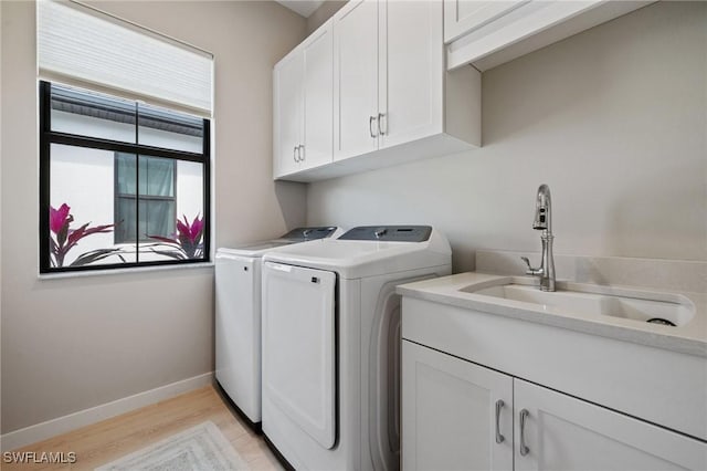 laundry room featuring separate washer and dryer, a sink, baseboards, light wood-type flooring, and cabinet space