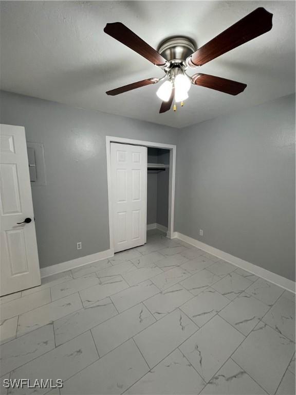 unfurnished bedroom featuring baseboards, marble finish floor, and a closet