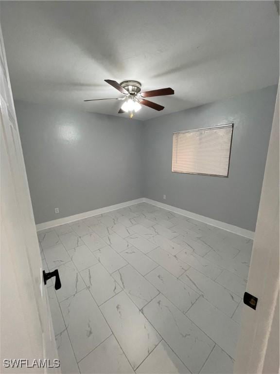 unfurnished room with a ceiling fan, baseboards, and marble finish floor