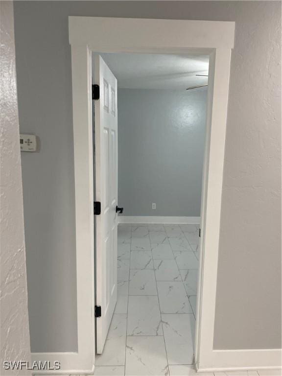 corridor with baseboards and marble finish floor