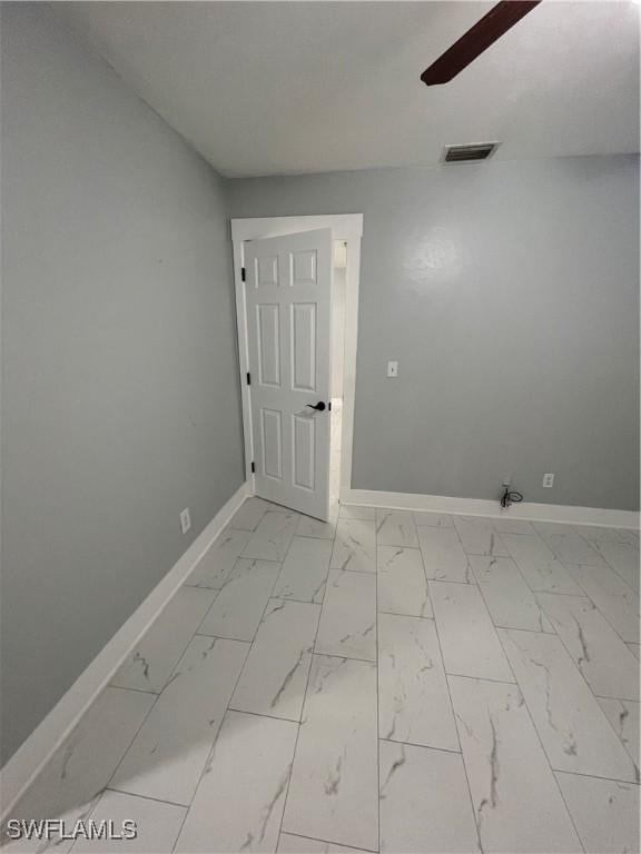 unfurnished room featuring visible vents, baseboards, marble finish floor, and a ceiling fan