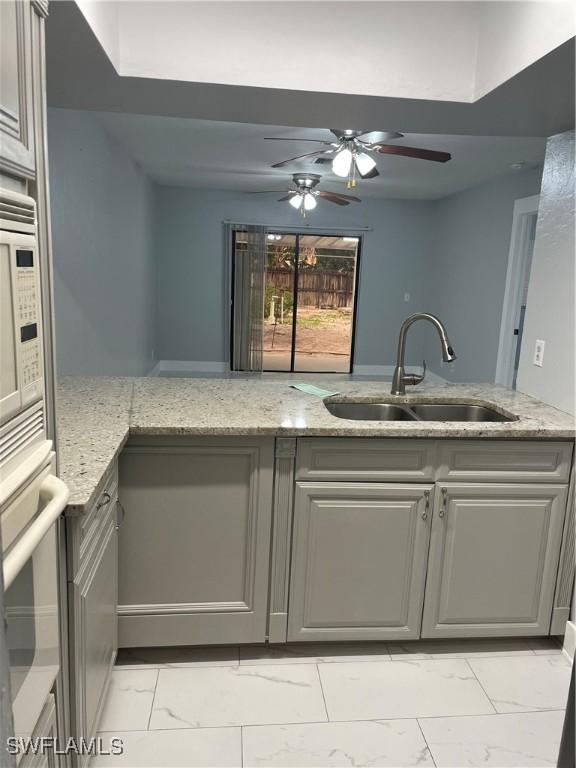 kitchen featuring a sink, light stone counters, marble finish floor, and stainless steel oven