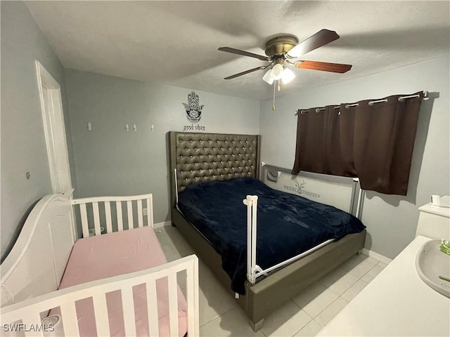 bedroom featuring tile patterned floors, baseboards, ceiling fan, and a sink