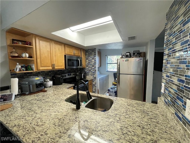 kitchen featuring a sink, decorative backsplash, light stone countertops, and appliances with stainless steel finishes