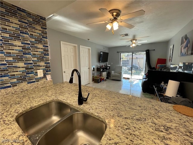 kitchen with open floor plan, light stone countertops, visible vents, and a sink