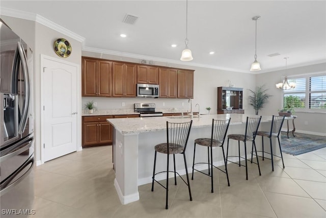 kitchen featuring visible vents, a kitchen breakfast bar, stainless steel appliances, brown cabinetry, and crown molding