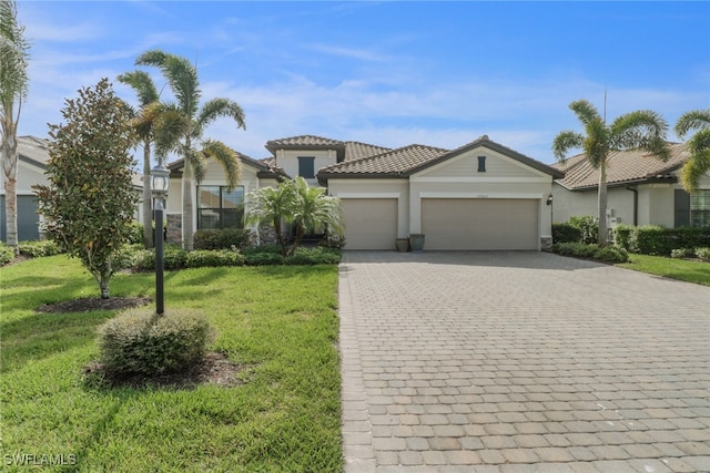 mediterranean / spanish-style house with a front lawn, a tiled roof, stucco siding, decorative driveway, and an attached garage