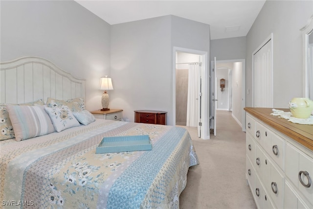 bedroom featuring ensuite bath and light carpet