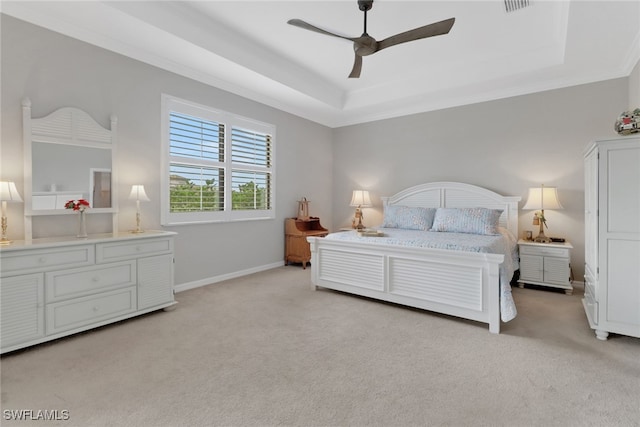 bedroom featuring light carpet, baseboards, a tray ceiling, and ornamental molding