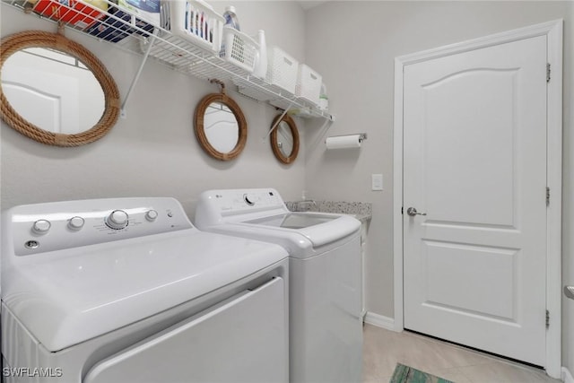 clothes washing area with baseboards, washing machine and dryer, and laundry area