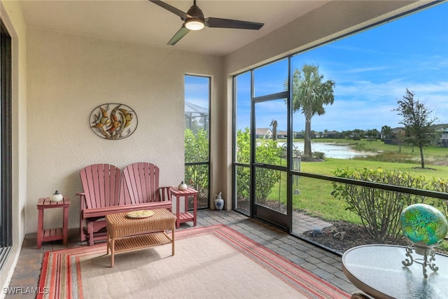 sunroom / solarium with a ceiling fan and a water view