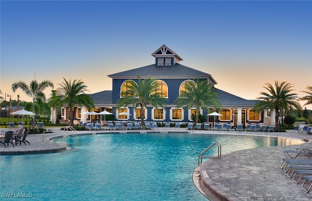 pool at dusk with a patio and a community pool