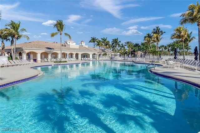 community pool with a patio area and fence