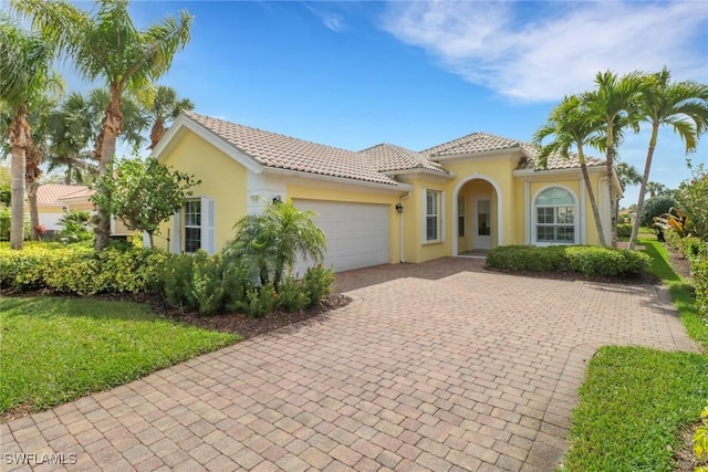 7710 Tommasi Ct, Naples, FL 34114 - mediterranean / spanish-style house featuring a garage, a tiled roof, decorative driveway, and stucco siding