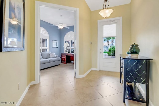 foyer featuring a ceiling fan, lofted ceiling, baseboards, and light tile patterned floors