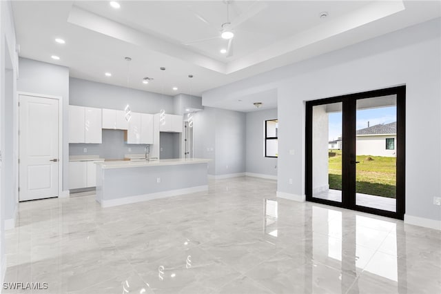 kitchen with marble finish floor, white cabinetry, a raised ceiling, and a sink