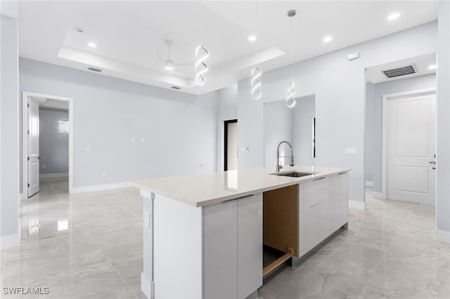 kitchen featuring a sink, marble finish floor, modern cabinets, and a raised ceiling