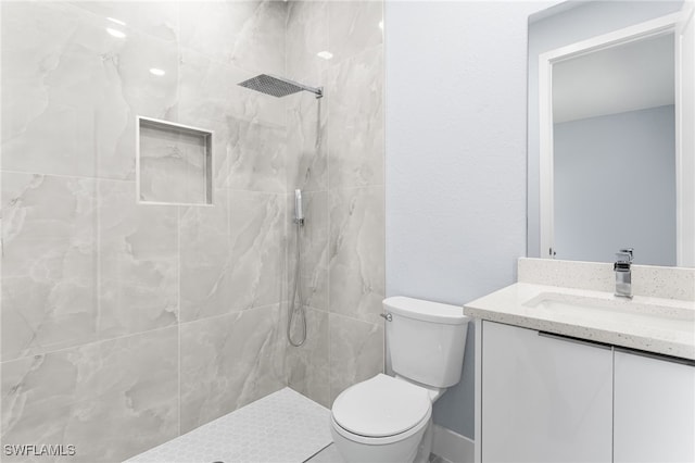 bathroom with a tile shower, vanity, and toilet