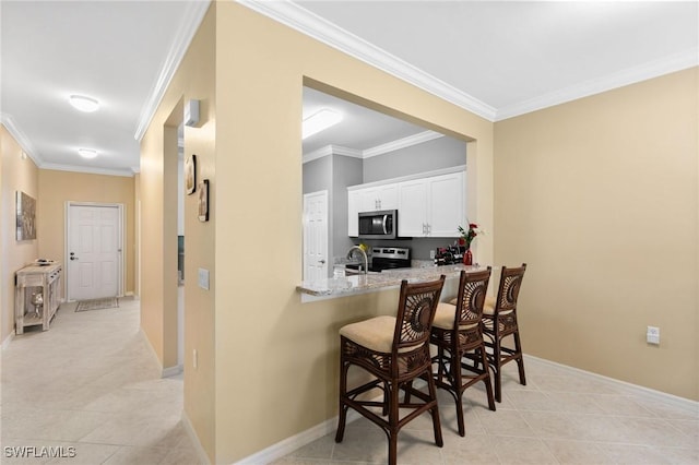 kitchen with light stone counters, a kitchen breakfast bar, stainless steel appliances, crown molding, and white cabinetry