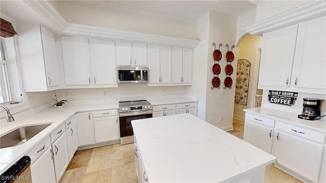 kitchen featuring arched walkways, ornamental molding, a sink, white cabinets, and appliances with stainless steel finishes