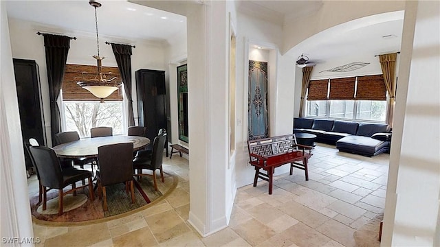 dining room featuring stone tile flooring, arched walkways, and a wealth of natural light