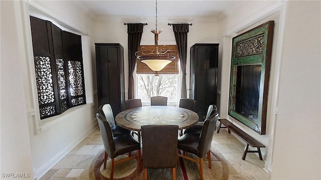 dining space with baseboards, stone tile flooring, and crown molding