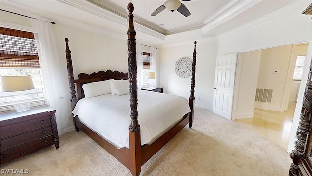 bedroom with a ceiling fan, visible vents, crown molding, a raised ceiling, and light colored carpet