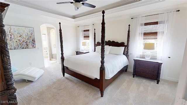 bedroom with arched walkways, multiple windows, light carpet, and a raised ceiling