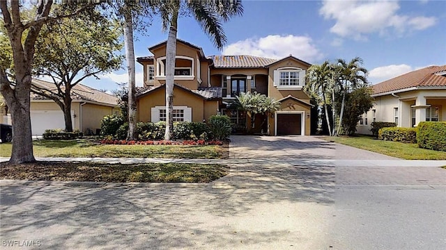 mediterranean / spanish house featuring stucco siding, driveway, a tile roof, and a garage