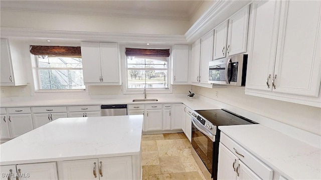 kitchen with crown molding, stone tile floors, appliances with stainless steel finishes, white cabinets, and a sink