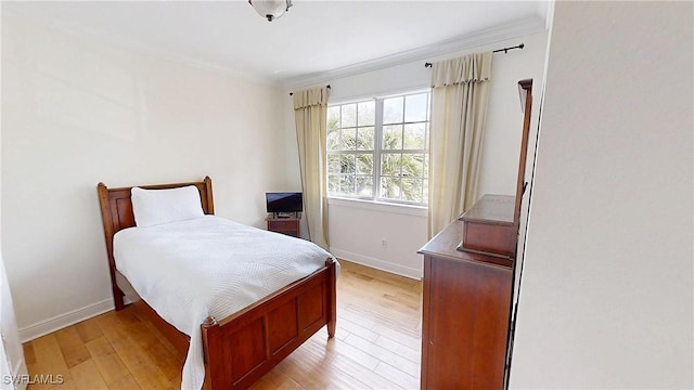 bedroom with crown molding, baseboards, and light wood finished floors