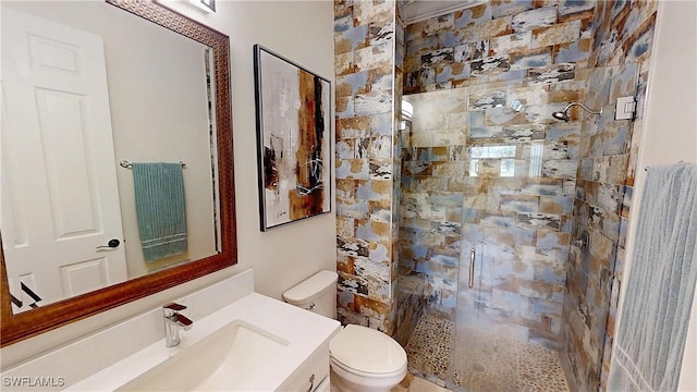 bathroom with tiled shower, toilet, and vanity