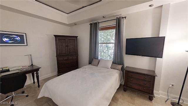 bedroom featuring baseboards, a tray ceiling, and ornamental molding