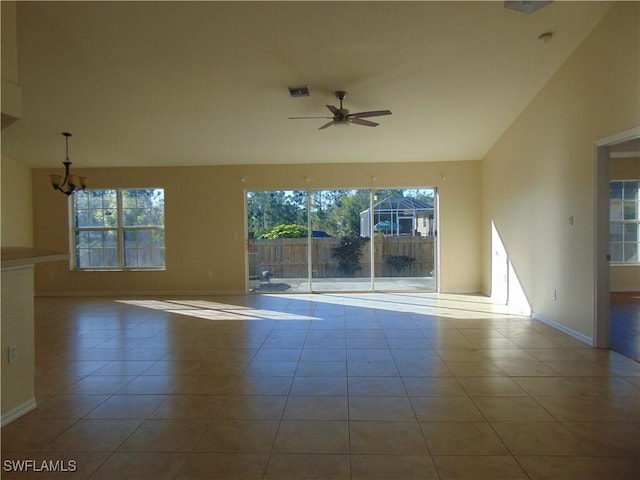 empty room with tile patterned floors, visible vents, plenty of natural light, and ceiling fan with notable chandelier