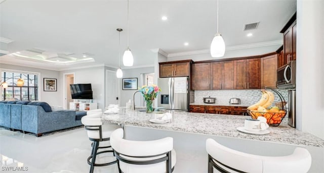 kitchen featuring visible vents, light stone counters, stainless steel appliances, pendant lighting, and backsplash