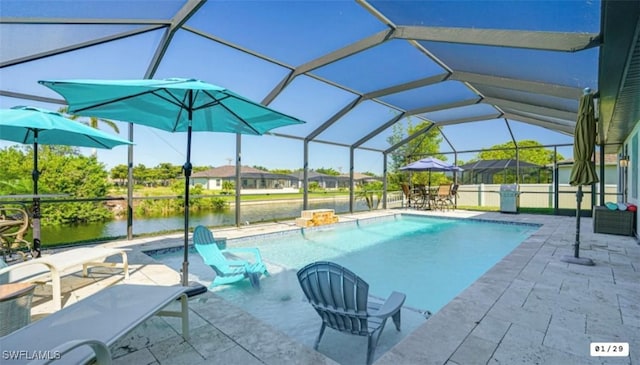 pool with glass enclosure, a patio area, and a water view