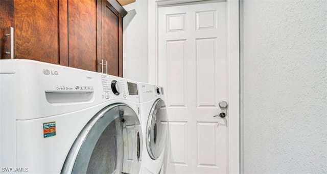 laundry area with washing machine and clothes dryer and cabinet space