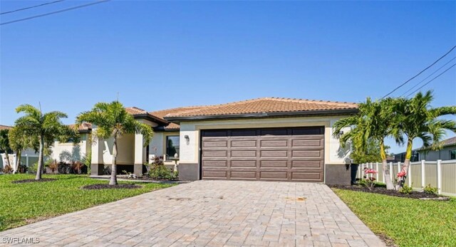 view of front of property featuring a garage, fence, a front lawn, and stucco siding