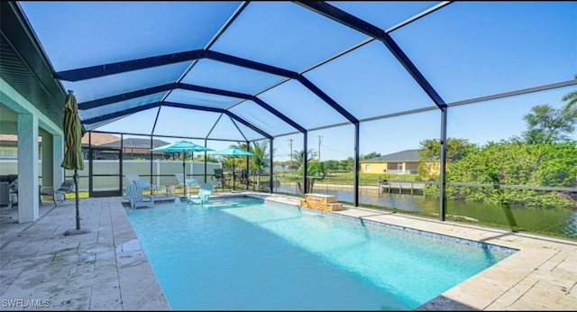 outdoor pool with glass enclosure, a patio area, and a water view