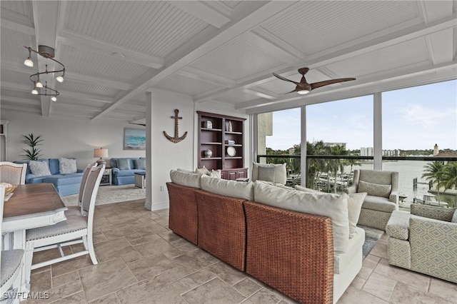 living room featuring beamed ceiling, coffered ceiling, a ceiling fan, and stone tile floors