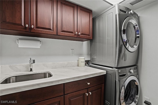 washroom with cabinet space, a sink, and stacked washer and clothes dryer