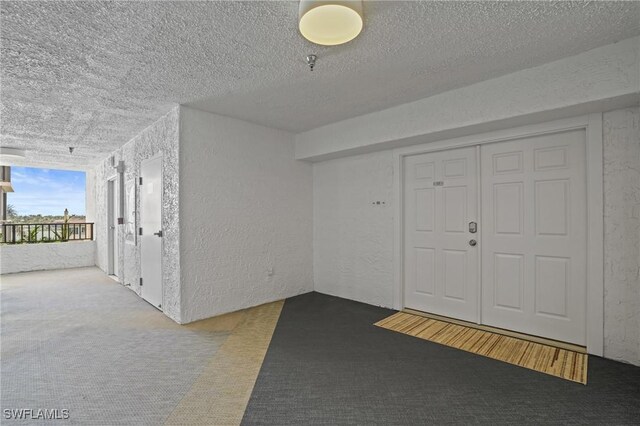 entryway featuring a textured wall and a textured ceiling