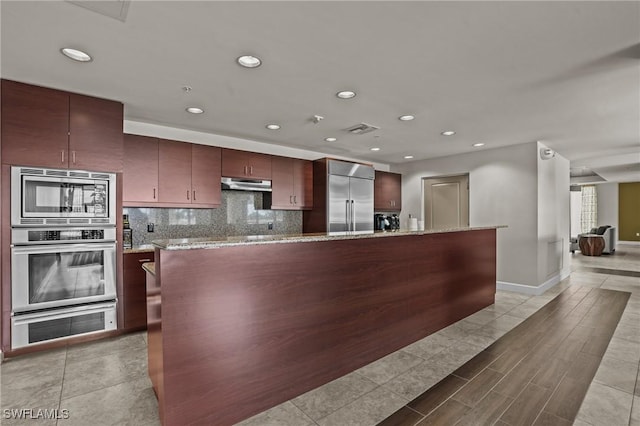 kitchen featuring tasteful backsplash, visible vents, built in appliances, under cabinet range hood, and recessed lighting