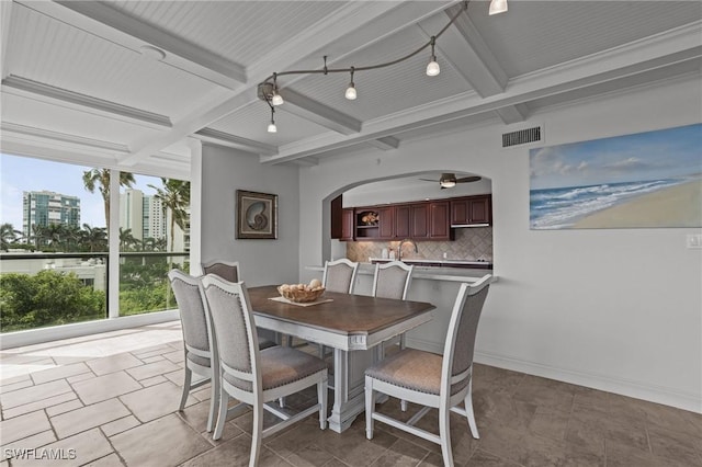 dining space featuring arched walkways, beam ceiling, visible vents, coffered ceiling, and baseboards