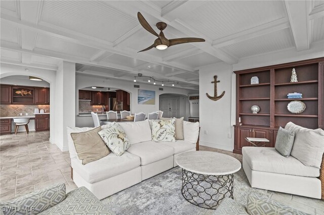 living room featuring baseboards, arched walkways, coffered ceiling, and a ceiling fan