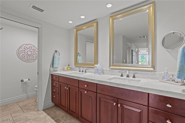 bathroom with toilet, double vanity, a sink, and visible vents